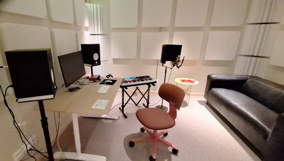 Skrivbord och en rosa skrivbordsstol. Datorskärmar och ett keybord samt högtalare.
