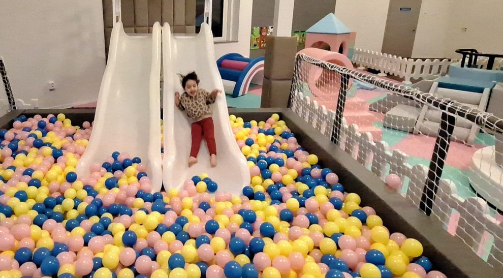 Flick aåker ner för en vit rutschkana ner i ett hav med bollar i gult, blått och rosa