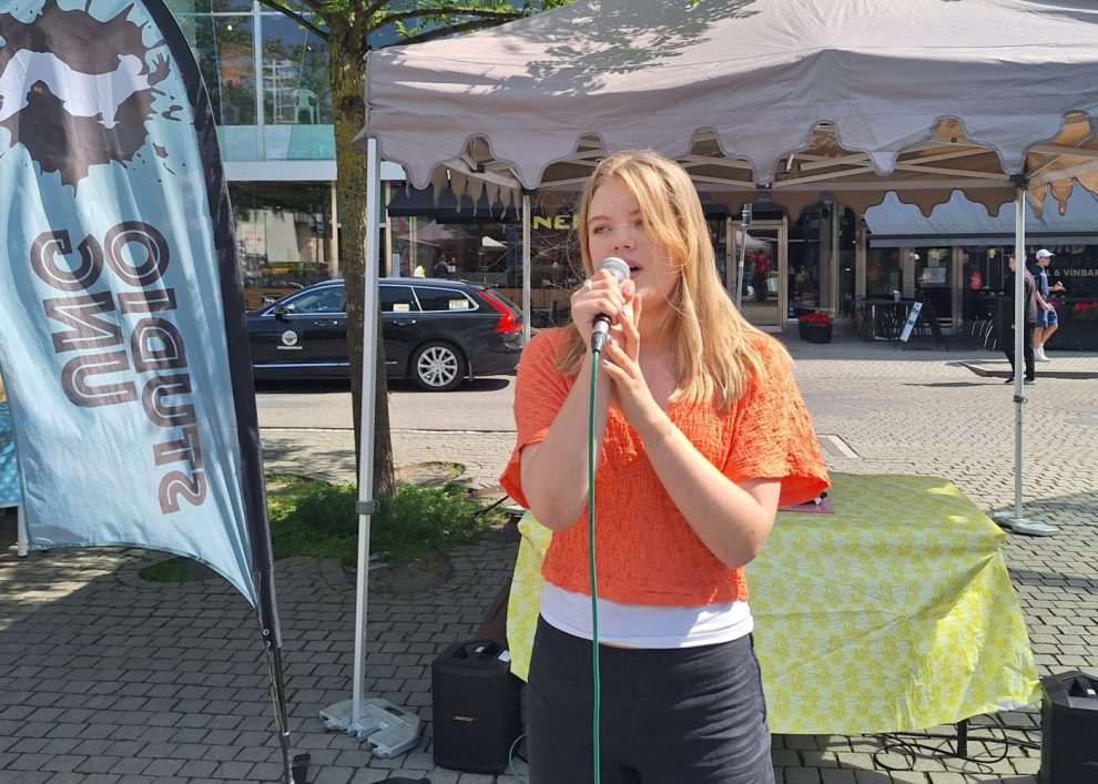 En vit kvinna i rödlätt långt hår, orange tröja