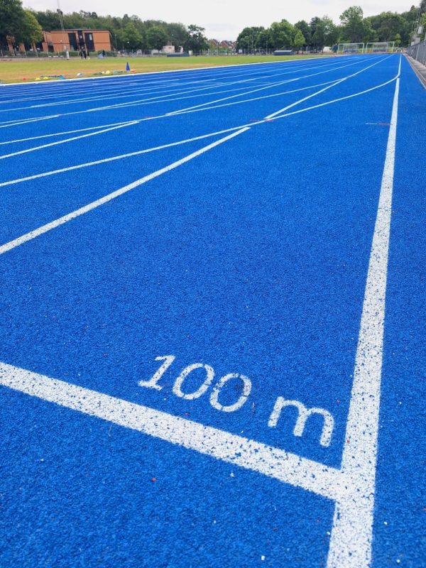 En nyanlags blå löparbana med ett streck där det står 100 meter.