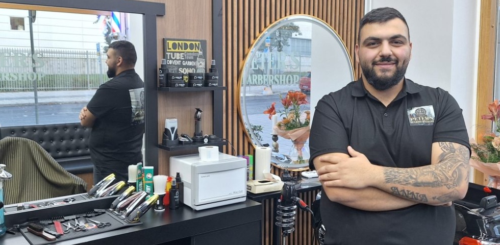 En salong med stora speglar, träpanel på väggarna. En icke vit man med mörkt kort hår och skägg.