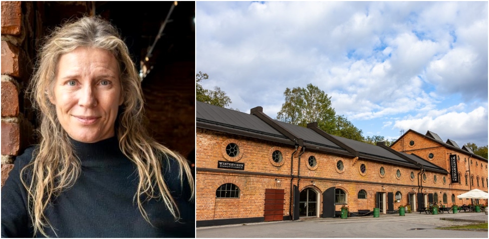 blond kvinna i mörk tröja intill en ljus tegelbyggnad