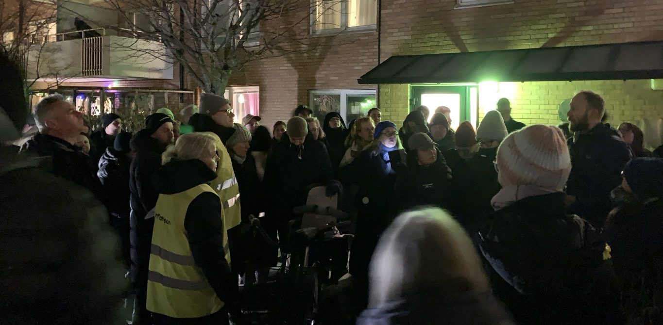 cirka 50 personer i vinterkläder på en mörk innergård