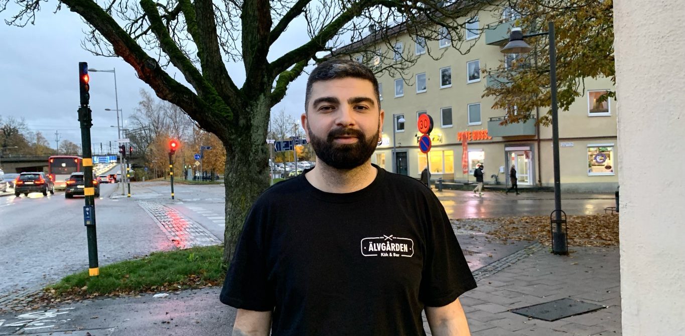 kortklippt man med skägg, klädd i en svart t-shirt, framför ett träd i höstskrud.