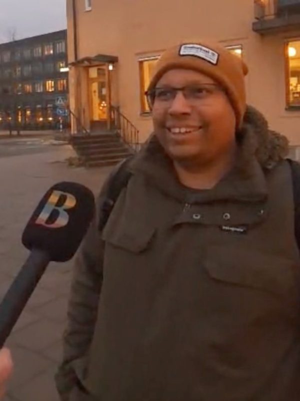Bild på en leende man och en mikrofon som hålls upp framför