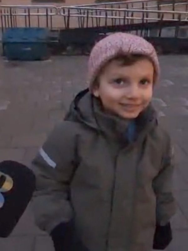 Bild på ett barn med en mössa och jacka, och en mikrofon som hålls upp framför