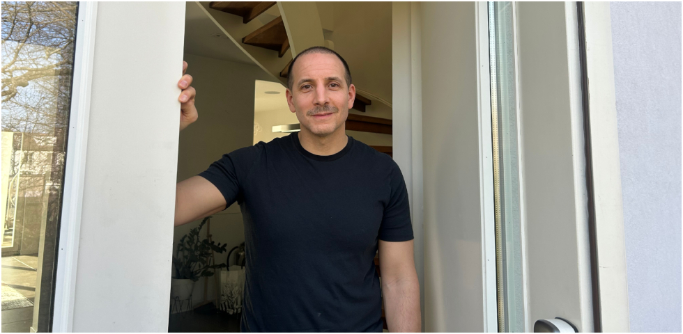 Bild på man med svart tröja som står o ler