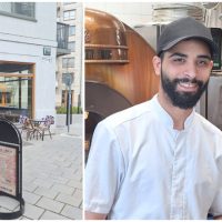 Till vänster en vit hörnfasad med stora fönster och cakestolar utanför. Till vänster en man i keps, vit kockskjorta och svart skägg och en kvinna i svart tshirt med brunt hår uppsatt.