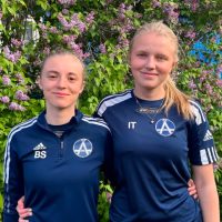 Två tjejer i fotbollskläder utomhus