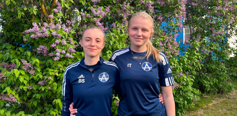 Två tjejer i fotbollskläder utomhus